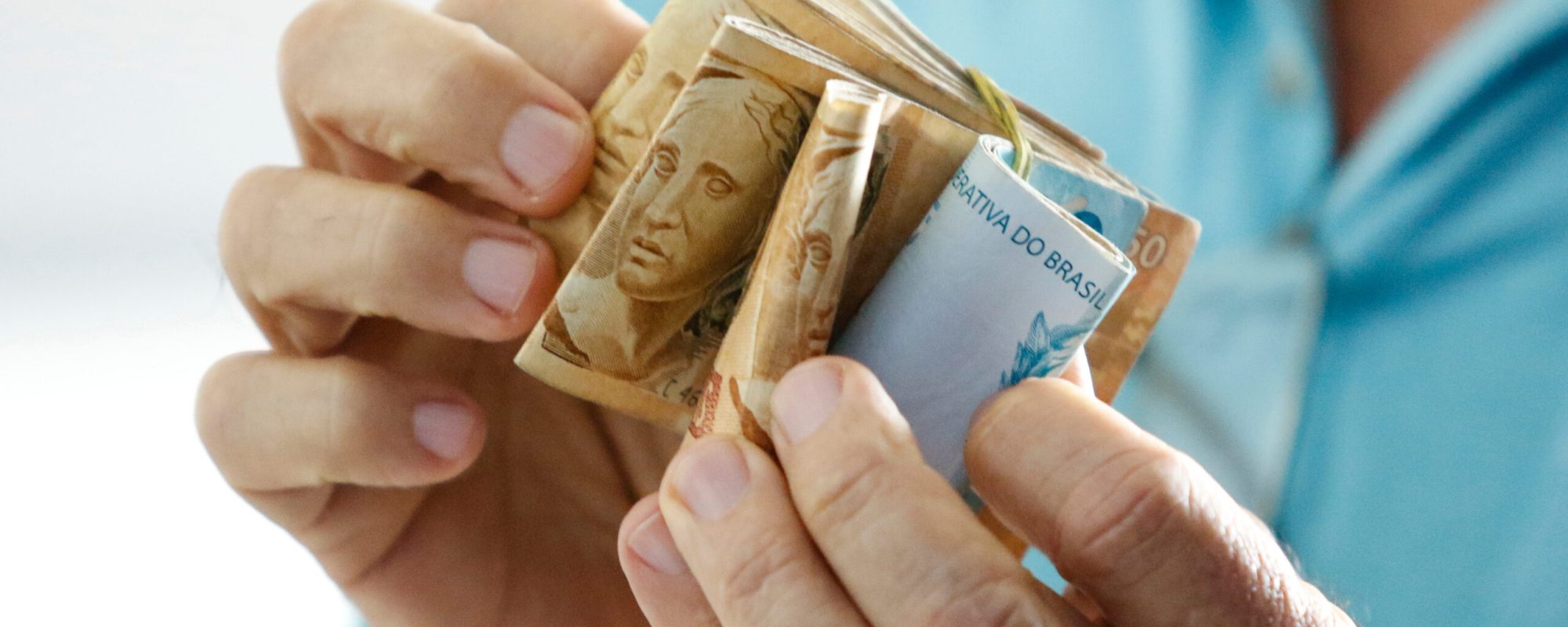 Hands holding Brazilian real notes, money from Brazil, notes of Real, Brazil BRL banknote, Brazilian currency, economy, income and business.
