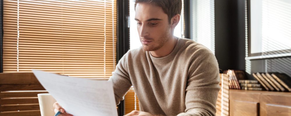 Picture of attractive young man in office working with documents. Coworking.