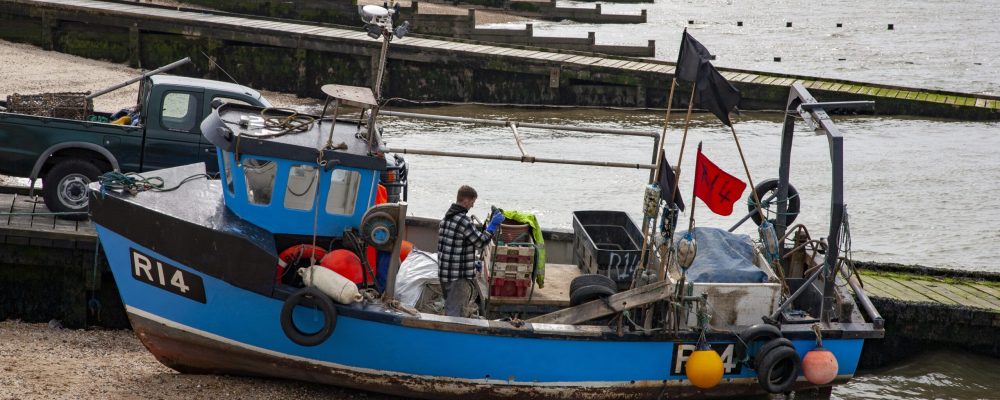 WHITSTABLE, KENT, UK, UNITED KINGDOM - Apr 17, 2013: Fishing boat on beach being prepared for next trip.