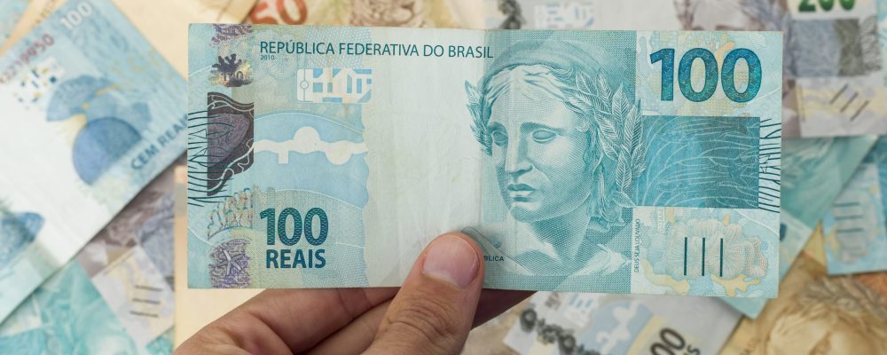 Brazillian Money, man holding 100 Reais notes.