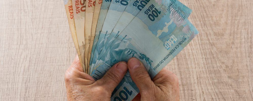 Brazilian currency: Real. Money from Brazil. Top view of old woman's hand handling bills.