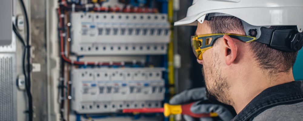Man, an electrical technician working in a switchboard with fuses. Installation and connection of electrical equipment.