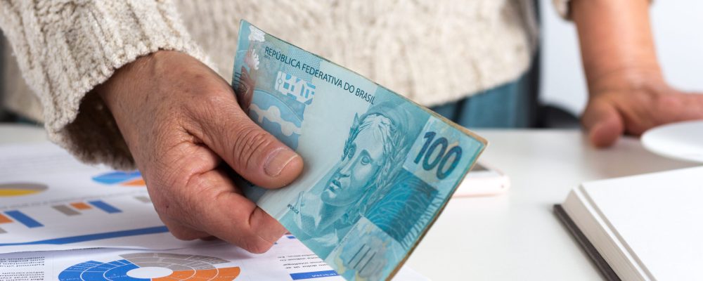 Paper notes from Brazil. Brazilian cash. Person giving papernotes on desk.