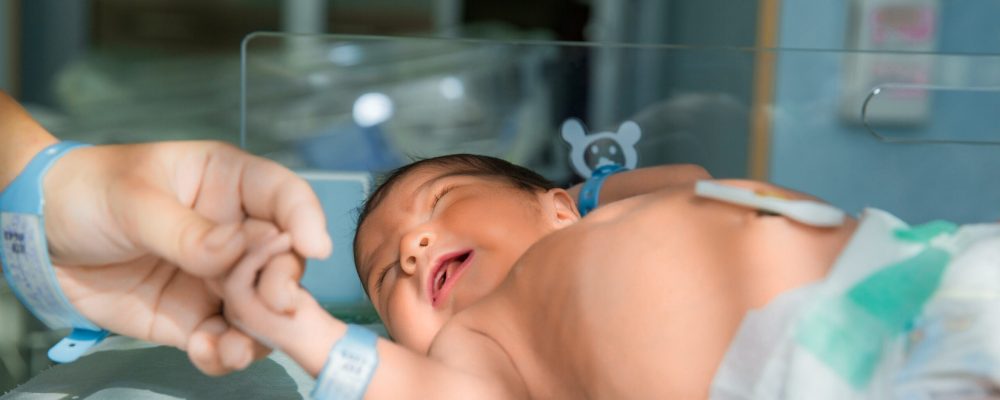 father holds hand of newly born babe in diapers