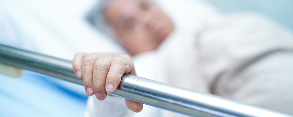 Asian senior or elderly old woman patient lie down handle the rail bed with hope on a bed in the hospital.